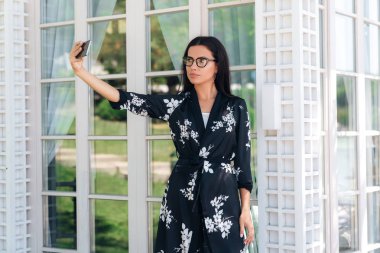 Güzel bir genç kız ayakta dışında selfie onun Smartphone'da yapma şık elbiseli Close-up. Becerikli, teknoloji halkı kavramı.