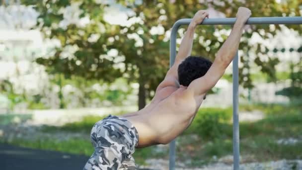 El atleta en el campo de deportes se calienta antes del entrenamiento. Un hombre musculoso va a practicar deportes al aire libre. El tipo con pantalones del ejército hace los ejercicios. Entrenamiento conceptual, crossfit, fitness, saludable . — Vídeos de Stock