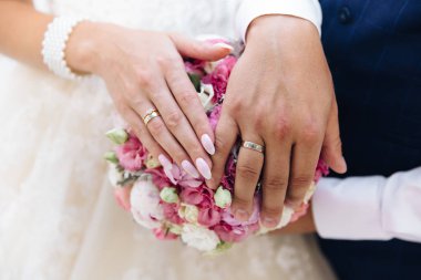 Yakın çekim yeni evlilere Nikah yüzükleri ile el hafifçe dokun peonies düğün buket.