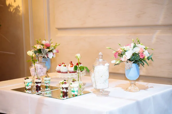 Candy bar, стол со сладостями и десертами на столе. Шведский стол с вкусными кексами, пирожными, печеньем, цветами . — стоковое фото