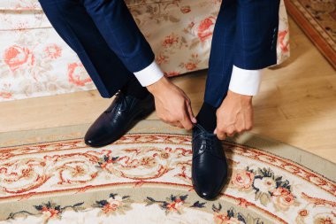 Yakın çekim yakışıklı bir adamın üzerinde siyah Ayakkabı bağcıklarımı bağla. Mavi pantolon ve çorap bir işadamı ofiste işe gitmeden Ayakkabı giymiyor. Kavramını moda giyim ve ayakkabı.