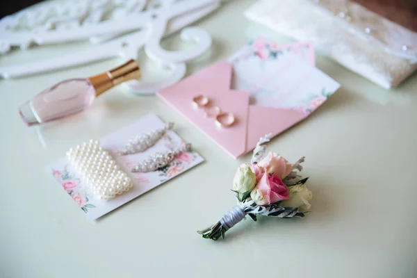 Bruiden set bruiloft accessoires, parfum en oorbellen bij bloemen achtergrond op tafel. Concept van juwelen. — Stockfoto