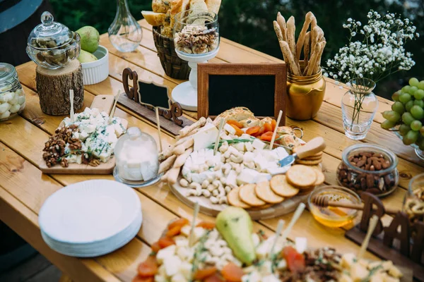 Barra de queijo close-up de vários tipos de queijo, lanches, mel, nozes decoradas em mesa de madeira na festa de casamento. Conceito de alimento . — Fotografia de Stock