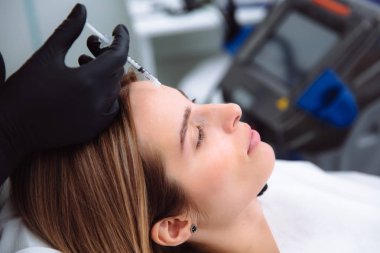 Yakın çekim güzel yüz ve kozmetik eller yüz güzelliği enjeksiyonlar sırasında şırınga. Gençleştirme ve hydratation. Klinik kozmetik kavramı.