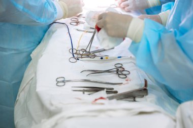 Yakın çekim cerrahi aletler cerrahi kliniğinde tıbbi bir tablo. Metal steril makas, kelepçe, cerrahi iğne masada ya da doktor elinde. Sağlık, araçları kavramı.