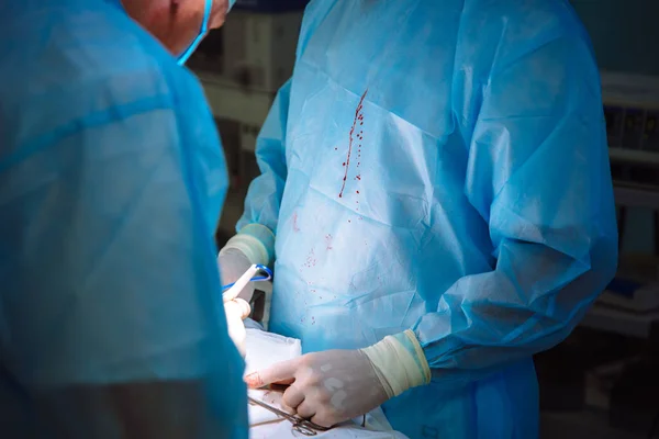 Dois médicos do sexo masculino em roupas médicas estéreis realizam uma operação em um hospital. A equipe profissional trabalha em uma clínica, um cirurgião com um assistente. O conceito de saúde, medicina . — Fotografia de Stock