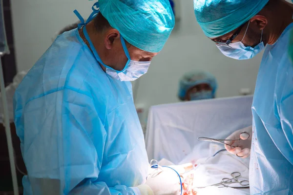 Dois médicos do sexo masculino em roupas médicas estéreis realizam uma operação em um hospital. A equipe profissional trabalha em uma clínica, um cirurgião com um assistente. O conceito de saúde, medicina . — Fotografia de Stock