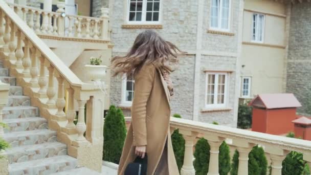 The shining happy girl finally flew to Europe, walks through the old streets, visits tours, studies ancient castles. The woman wears a long coat and hat, is cool and enjoys her vacation. — Stock Video