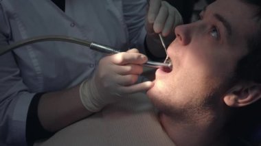Steril bir maske ve giysi bir dişçi kadında yordamlar ile tıp aletleri hastaların ağzına gerçekleştirir. Bir diş kliniğinde diş tedavisi. Sağlık kavramı.