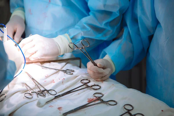 Detail chirurgické nástroje na lékařský stůl na klinice během operace. Kovové sterilní nůžky, svorky, chirurgické jehly u stolu nebo v rukou lékaře. Pojem zdraví, nástroje. — Stock fotografie