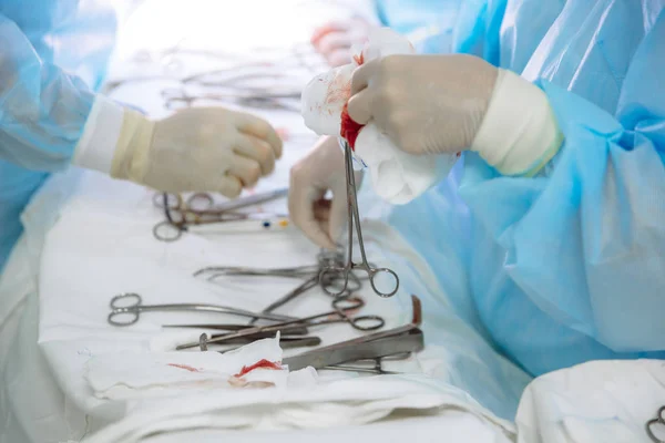 Detail chirurgické nástroje na lékařský stůl na klinice během operace. Kovové sterilní nůžky, svorky, chirurgické jehly u stolu nebo v rukou lékaře. Pojem zdraví, nástroje. — Stock fotografie