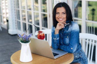 Güzel bir genç kadın Avrupa bir görünüme sahip, bir kredi banka kartı elinde tutan, o internette alışveriş ve onun emir için ödemek mutlu.