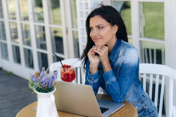 Schüchternes verwirrtes Mädchen lächelt süß, einer der Besucher machte ihr ein Kompliment für ihr Aussehen. das Model beschäftigt sich mit seinen eigenen Angelegenheiten im Internet, arbeitet am Laptop, bezahlt etwas im Internet. — Stockfoto