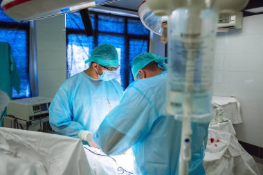 Steril Tıbbi giysili iki Doktor hastanede bir işlem gerçekleştirin. Profesyonel iş klinikte, cerrahlar bir Yardımcısı kadın erkeklerle. Sağlık, tıp kavramı.