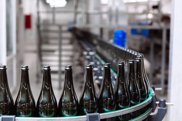 Glass bottles on the automatic conveyor line at the champagne or wine factory. Plant for bottling alcoholic beverages.