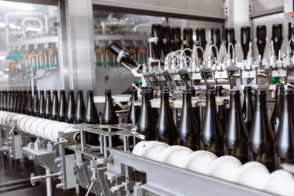 Botol kaca pada baris konveyor otomatis di pabrik sampanye atau anggur. Tanaman untuk botol minuman beralkohol . — Stok Foto