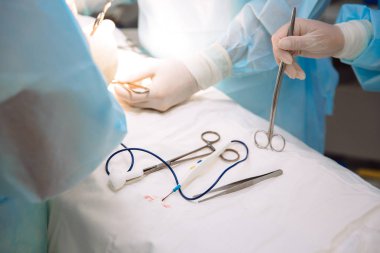 Yakın çekim cerrahi aletler cerrahi kliniğinde tıbbi bir tablo. Metal steril makas, kelepçe, cerrahi iğne masada ya da doktor elinde. Sağlık, araçları kavramı.