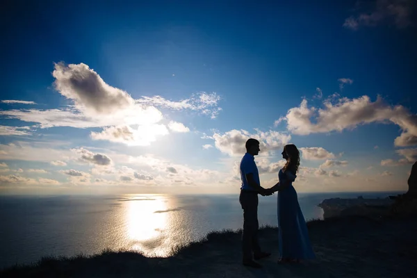 夕暮れ時の愛情のあるカップルのシルエットです。男は海を見下ろす高山の女性を抱きしめます。コンセプト家族、愛、結婚式、新婚旅行. — ストック写真