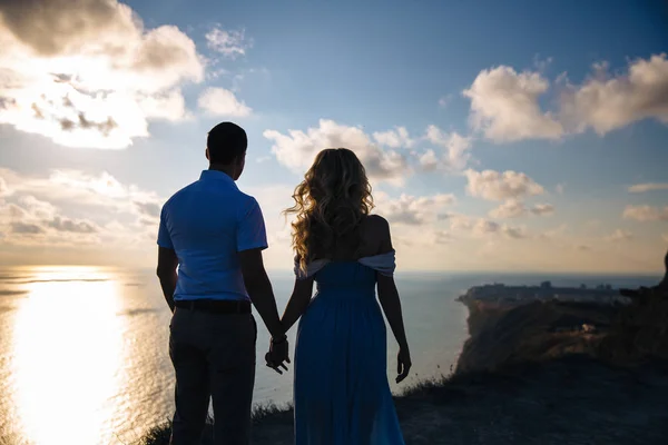 Silueta de una pareja amorosa al atardecer. Hombre abrazándose con una mujer en una alta montaña con vistas al mar. Concepto familia, amor, boda, viaje de luna de miel . — Foto de Stock