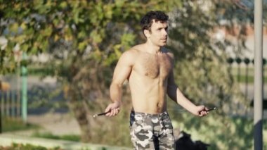 Ağır çekim, kamuflaj atlet spor alanında bir atlama ipi ile atlar pantolon. Kaslı adam spor egzersizleri yapmadan önce ısınma. Fitness kavramı, sağlık.