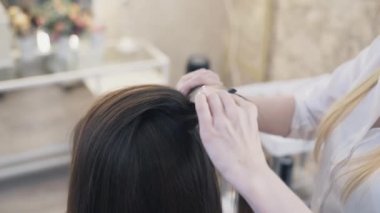 Yakın çekim, ağır çekim Kadın Kuaför saç sıkma bir saç ironer kullanan bir istemcinin bir saç kesimi var. İş yerinde profesyonel kuaför.