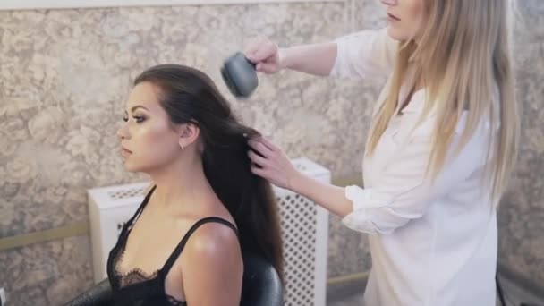 Une femme coiffeuse peigne les cheveux longs à un client et les prépare à effectuer des procédures avant de couper. Peigne entre les mains d'un styliste. Le concept de coupes de cheveux à la mode . — Video