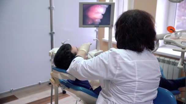 Een vrouwelijke tandarts een patiënt tanden met een intra-orale camera onderzoekt en de resultaten worden weergegeven op de monitor. Behandeling en preventie van cariës, dental ziekten, gezondheid concept. — Stockvideo