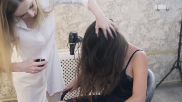 Detail, Zpomalený záběr dívka s dlouhými tmavými vlasy přišla kadeřnice udělat záchvat. Kadeřník kroutí její klient, stříká lakem pro fixaci. Lidé, salony krásy, make-up. — Stock video
