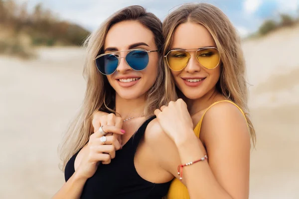 Retrato de cerca de dos hermosas chicas en trajes de baño abrazándose en la playa . — Foto de Stock