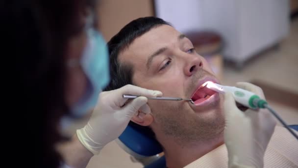 La dentista femenina de cerca examina los dientes de un paciente con una cámara intraoral. Tratamiento y prevención de enfermedades dentales, caries, concepto de salud . — Vídeo de stock