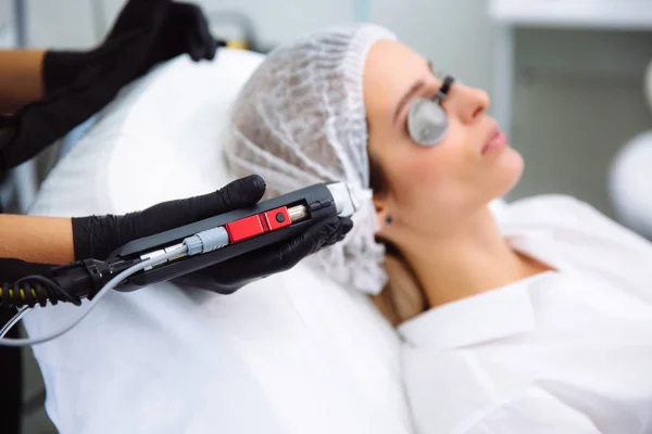 Косметолог-косметолог крупным планом проводит лазерное лечение лица молодой женщины, эпиляционные процедуры по удалению волос в салоне красоты SPA . — стоковое фото