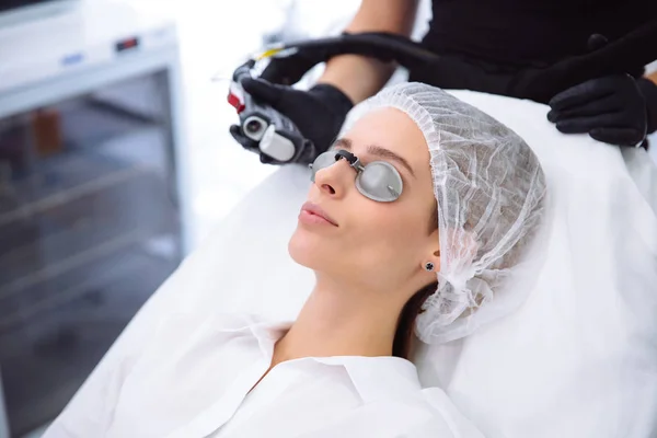 Крупным планом косметолог проводит лазерное лечение лица молодой женщины, эпиляционные процедуры по удалению волос в салоне красоты . — стоковое фото