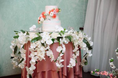 Çok düzeyli düğün pastası çiçeklerle süslenmiş bir masada duruyor. Yemek, tatlılar ve tatlılar bir partide kavramı.