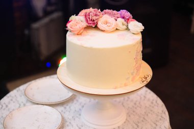 Çok düzeyli düğün pastası çiçeklerle süslenmiş bir masada duruyor. Yemek, tatlılar ve tatlılar bir partide kavramı.