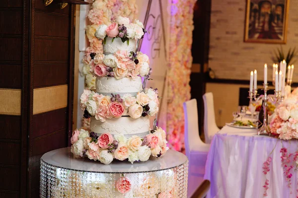 Çok düzeyli düğün pastası çiçeklerle süslenmiş bir masada duruyor. Yemek, tatlılar ve tatlılar bir partide kavramı. — Stok fotoğraf