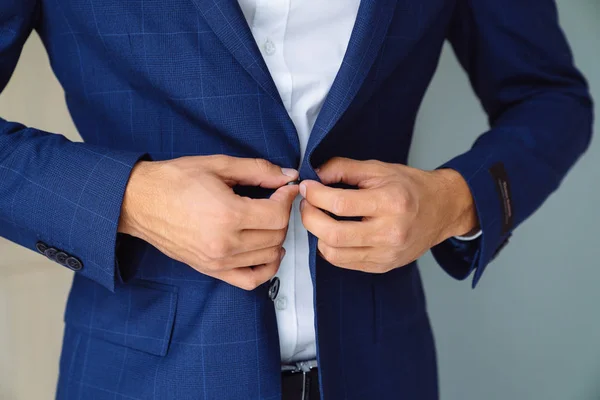 Крупный бизнес стильный мужчина застегивает свою голубую куртку, стоя в стильном офисе с дизайнерским ремонтом . — стоковое фото