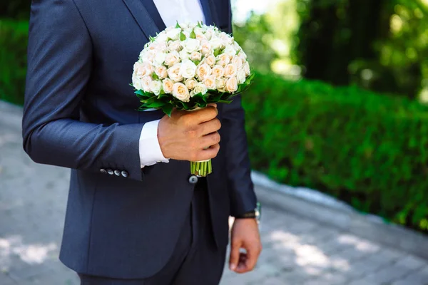 Gros plan d'un cadre recadré est un bouquet tendre de roses dans les mains du marié. Un homme en robe de mariée tient des fleurs . — Photo