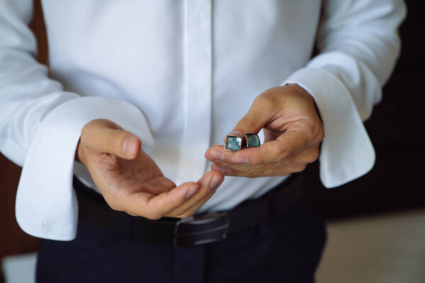 Closeup businessman hands with cufflinks. Man in a business suit, white shirt. Preparing the groom on the wedding day