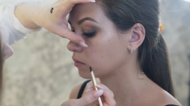 Make-up artists εργασία έννοιας, μακιγιάζ. Γκρο πλαν μακιγιάζ χρώματα προσεκτικά το eyeliner με το eyeliner, οπτικά ανοίγει τα μοντέλα μοιάζουν με τη βοήθεια του eyeliner. — Αρχείο Βίντεο