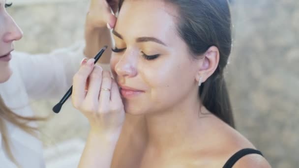 Make-up-Artist bemalt die Augenbrauen einer Kundin mit einem braunen Bleistift. Konzept für Schönheitssalons, Visagisten. — Stockvideo