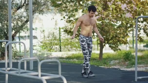 Jeune athlète saute avec une corde à sauter sur le terrain de sport dans le parc d'été — Video