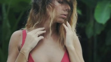 Kırmızı mayo ağır çekim yakın çekim seksi modelinde saçlarını dokunur.