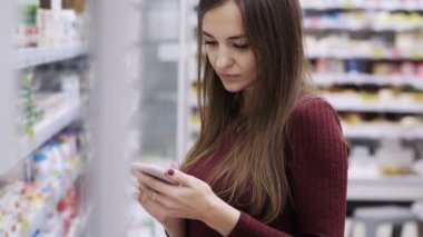 Genç çekici kadın akıllı süpermarkette listesi yapmak için kontrol