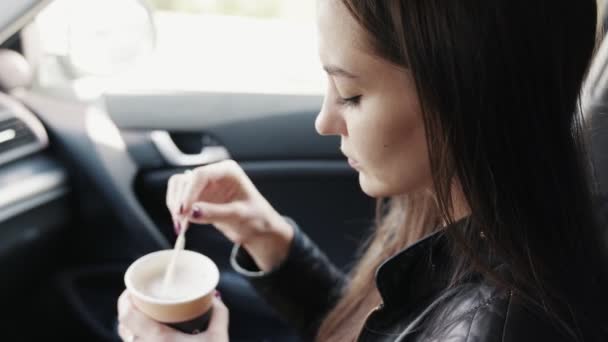 Szép lány ül az autóban csésze kávéval a kezében — Stock videók