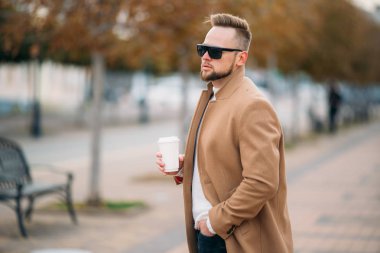 Sakallı yakışıklı genç Park, kopya alanı Kupası kahve içme güneş gözlüğü