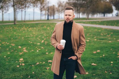 Sakallı yakışıklı genç Park, kopya alanı Kupası kahve içme güneş gözlüğü