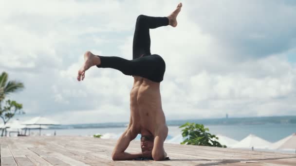 Człowiek robi ćwiczenia jogi z headstand na pięknej plaży. — Wideo stockowe