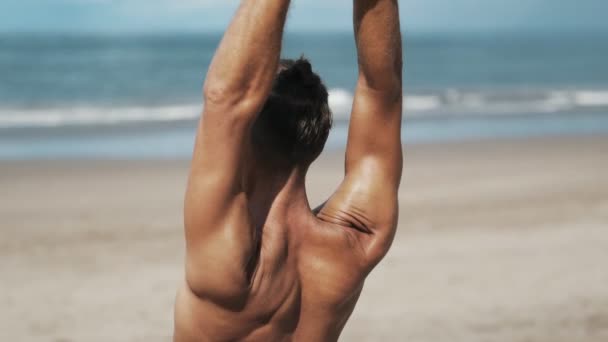 Achterkant weergave man met sportief lichaam doen yoga oefeningen met de oceaan achtergrond, close-up — Stockvideo