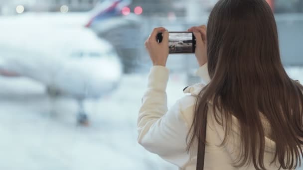 Tyłu widok kobieta bierze zdjęcie samolotu w pobliżu okna na lotnisko — Wideo stockowe