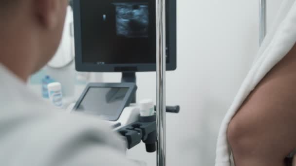 Ponto de vista médico faz um ultra-som nas pernas do paciente e olha para o monitor, de perto — Vídeo de Stock